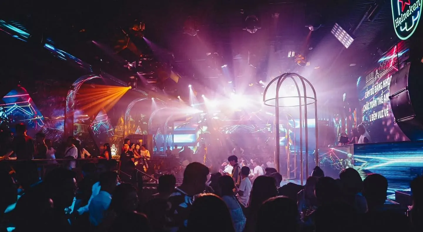 Sảnh 9E Club Phú Quốc nhìn về sân khấu — lồng vũ công, dàn đèn và khói sân khấu